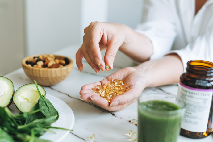 Mujer tomando un suplemento de vitamina D con sus alimentos.