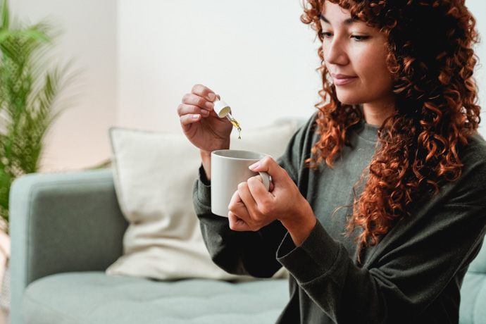 Mujer echando unas gotas de Kudzu en una taza.